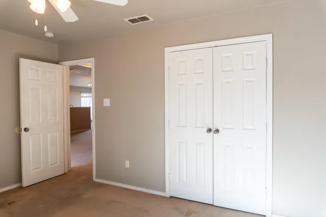 an empty room with a ceiling fan and windows