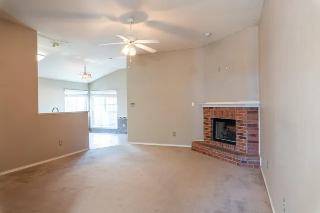 an empty room with windows and fireplace