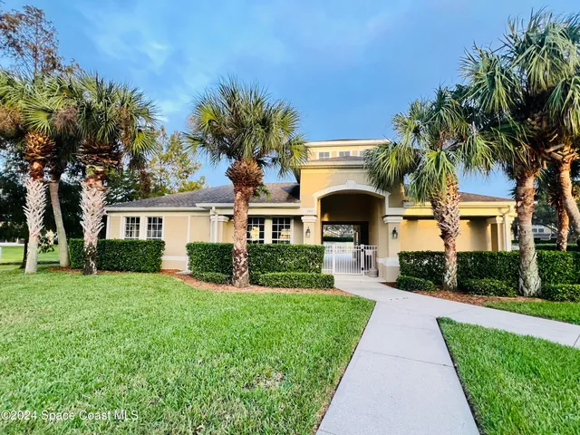 a front view of a house with a yard and potted plants