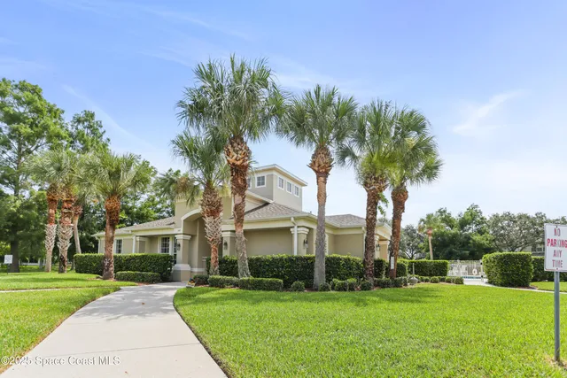 a front view of a house with a yard and palm trees