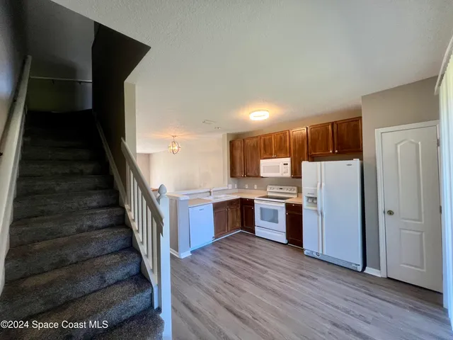 a view of a kitchen with wooden floor and electronic appliances