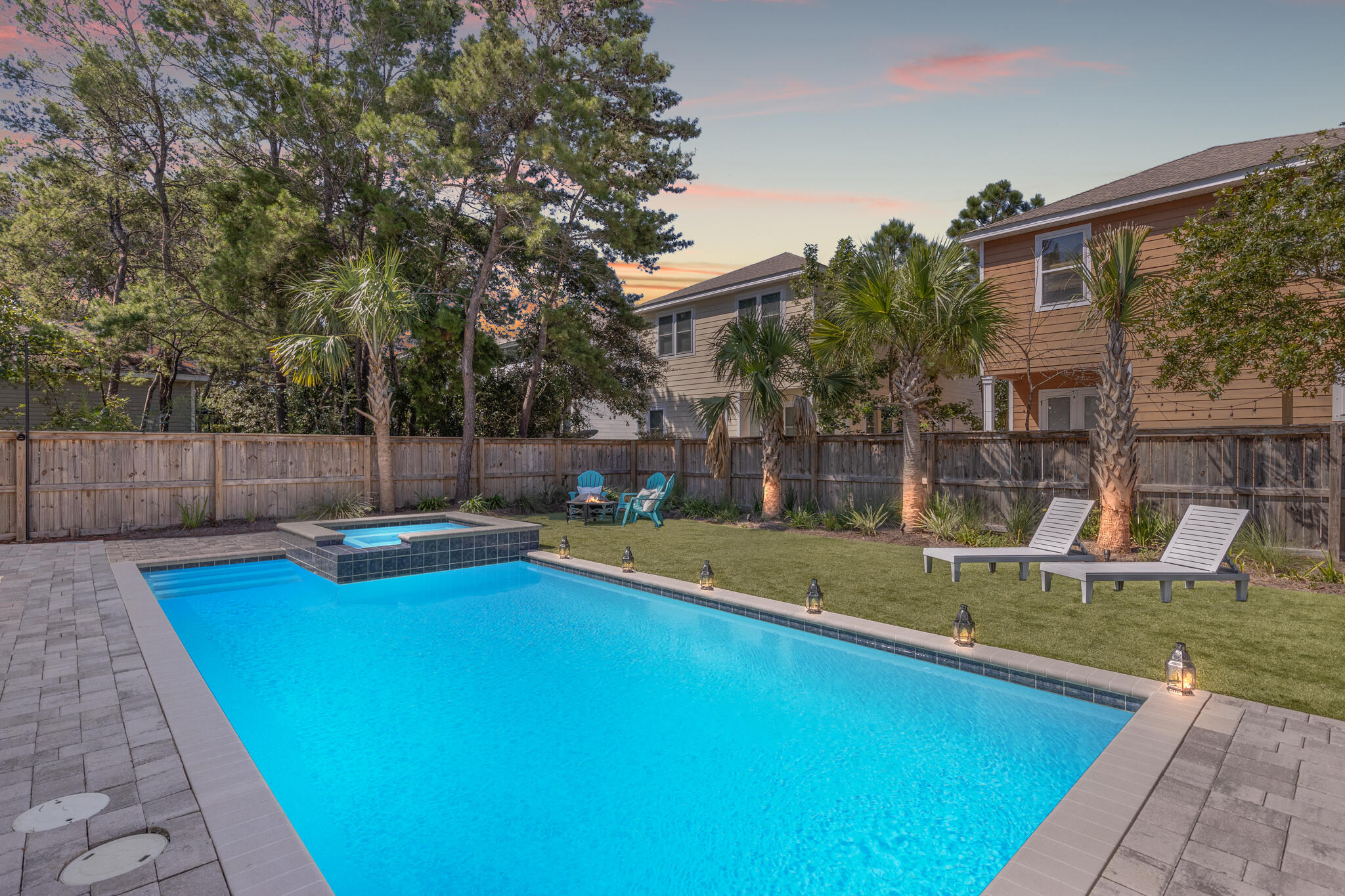 a view of swimming pool with seating space and trees in the background