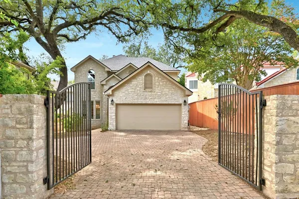 a view of a house with a small yard and a large tree