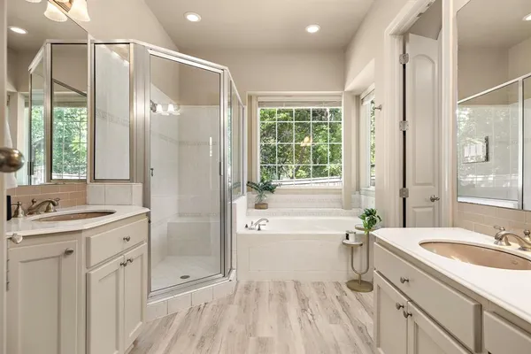 a spacious bathroom with a tub sink shower and a mirror