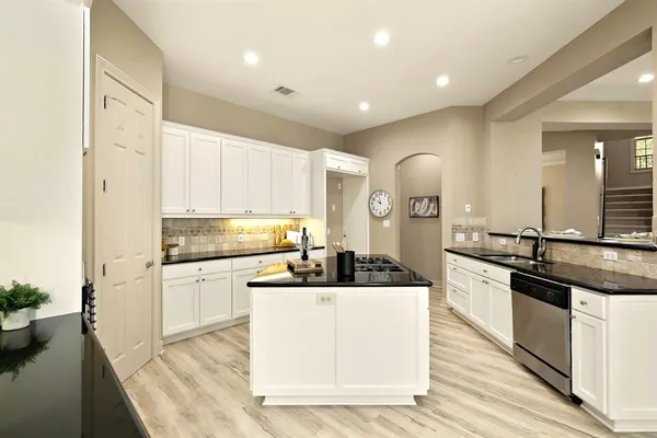 a kitchen with stainless steel appliances granite countertop a stove top oven a sink a counter space and cabinets
