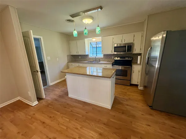 a kitchen with stainless steel appliances a refrigerator a sink a stove a microwave and wooden floor