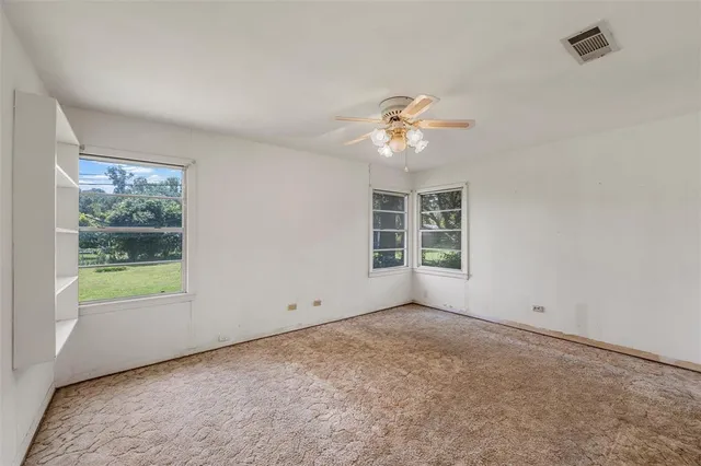 an empty room with windows and ceiling fan