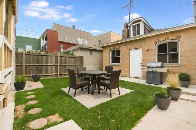a view of a patio with table and chairs potted plants and large tree