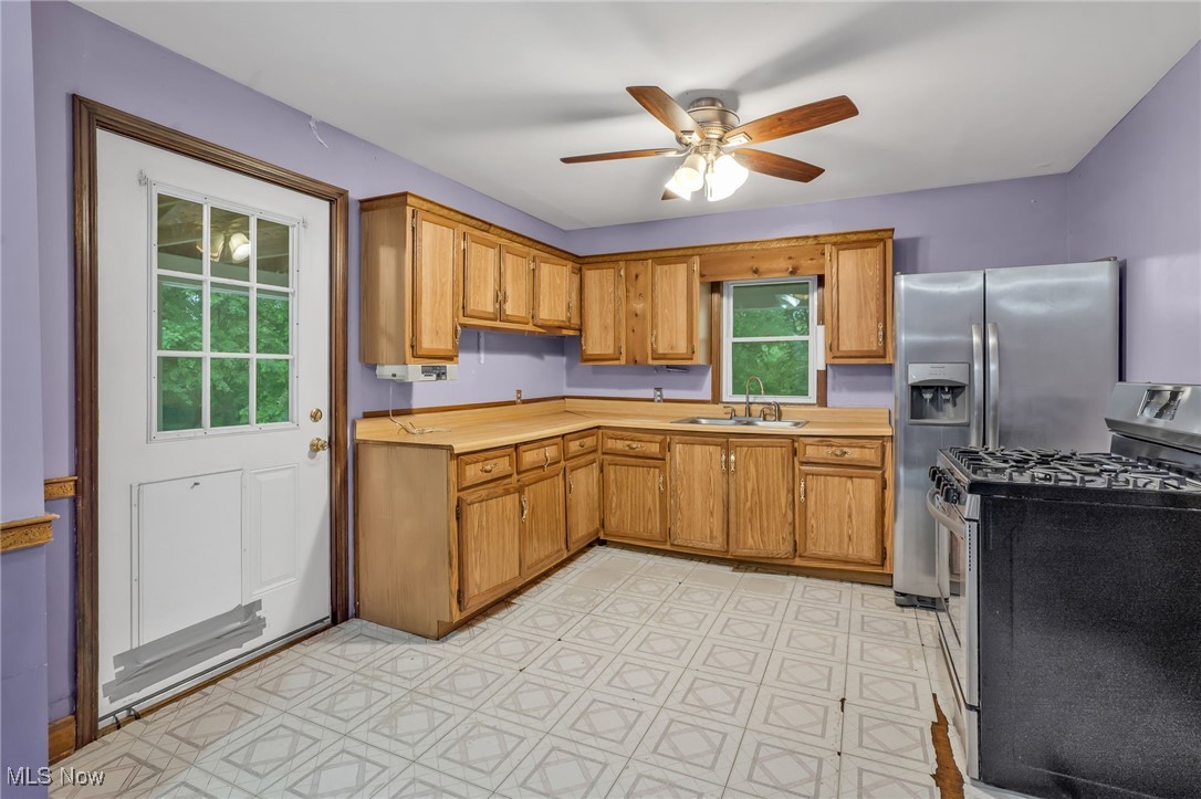 1901 Kimball Road Southeast Canton, OH 44707 - Photo 10 of 32 Kitchen featuring stainless steel gas range, a sink, light countertops, ceiling fan, and brown cabinets