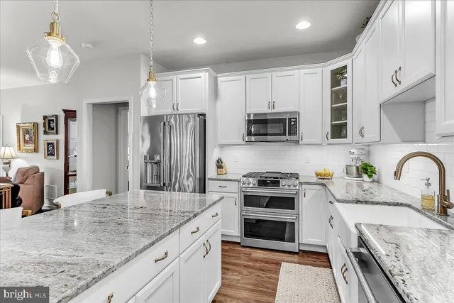 a kitchen with stainless steel appliances granite countertop a stove top oven a sink dishwasher a refrigerator and a oven with wooden floor