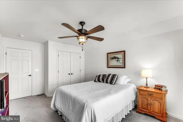 a bedroom with a bed and a lamp on dresser