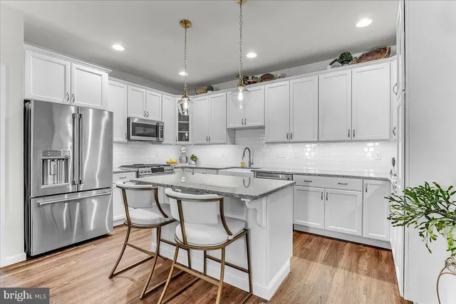 a kitchen with kitchen island granite countertop stainless steel appliances cabinets a sink and a potted plant