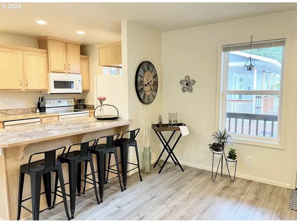 a very nice looking kitchen with granite countertop a stove a sink and a dining table with wooden floor