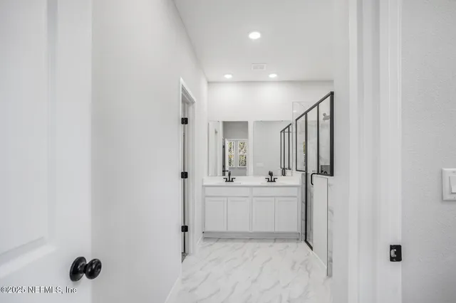a large white bathroom with a tub sink and mirror