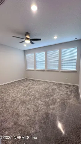 an empty room with a ceiling fan and window