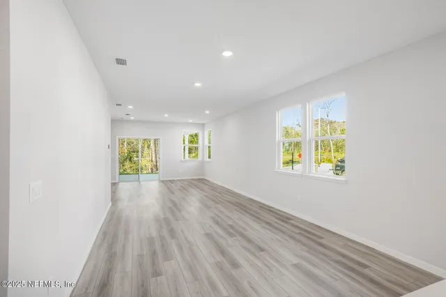an empty room with windows and wooden floor