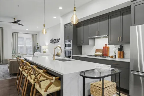 a kitchen with stainless steel appliances granite countertop a table chairs in it and wooden floors