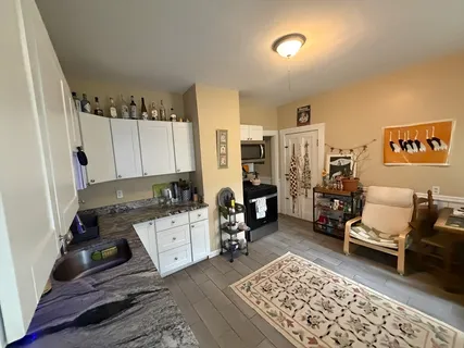 a kitchen with a refrigerator and wooden floor