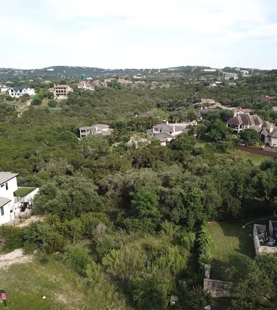 an aerial view of residential houses with outdoor space and trees