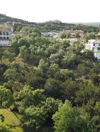 an aerial view of residential house with outdoor space and trees all around