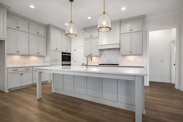 a kitchen with white cabinets stainless steel appliances and wooden floor