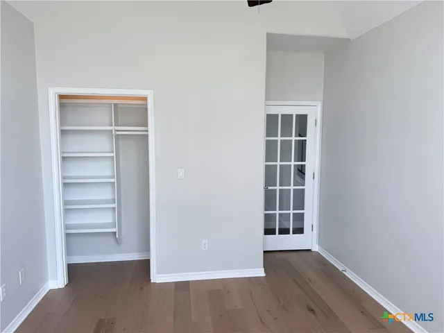 a view of an empty room with a window and wooden floor