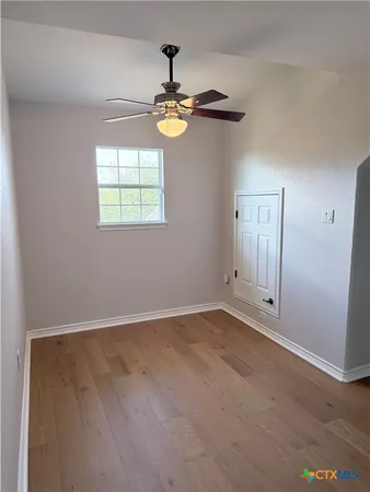 an empty room with windows and chandelier fan