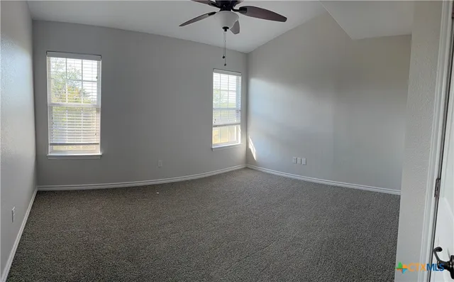 an empty room with a window and a ceiling fan