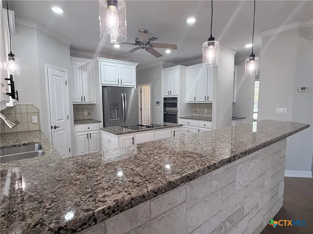 a large kitchen with kitchen island granite countertop a large counter top and stainless steel appliances