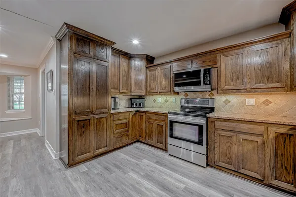 a kitchen with stainless steel appliances granite countertop a refrigerator a stove and a wooden floors