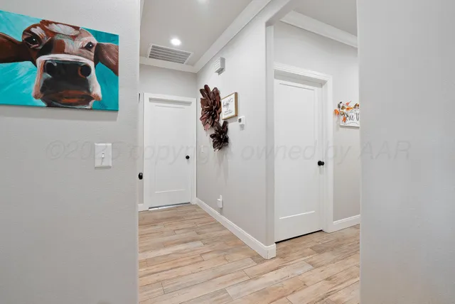 a view of a hallway to room with wooden floor