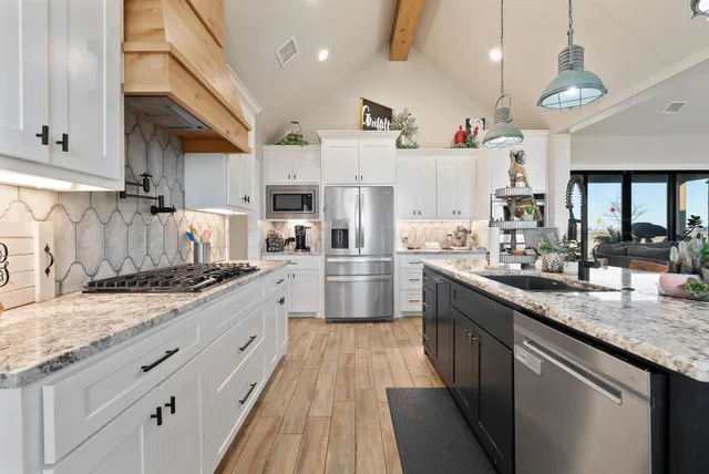 a large kitchen with stainless steel appliances granite countertop a lot of counter space and wooden floors