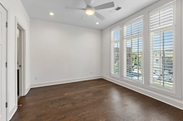 an empty room with wooden floor and windows with curtains