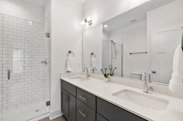 a bathroom with a double vanity sink mirror and shower