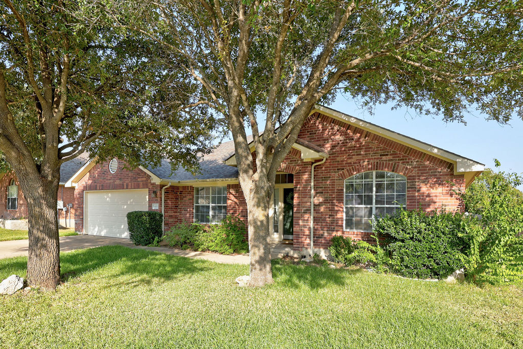 400 Ranier Lane Round Rock, TX 78665 - Photo 3 of 36 Mature shade trees frame the classic brick exterior and manicured lawn of this single-story home.