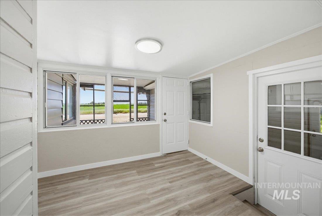 30013 Apple Valley Road Parma, ID 83660 - Photo 12 of 25 Enclosed porch featuring wood-finish flooring, white trim, light neutral walls, multiple windows, and two entry doors