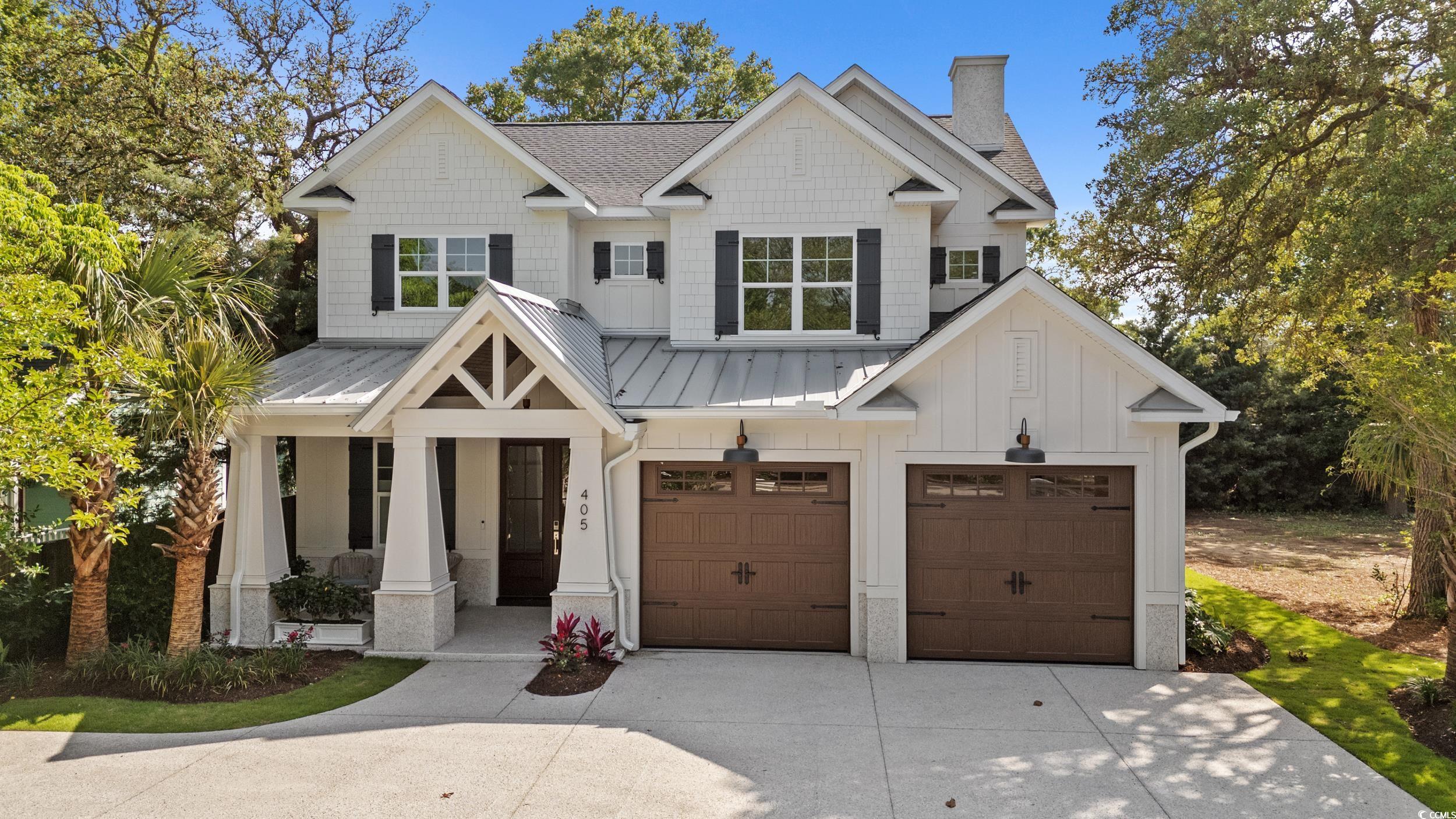 View of front of home featuring driveway, a porch, a chimney, an attached garage, and board and batten siding