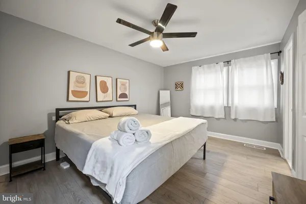 a bedroom with a bed and dresser with wooden floor
