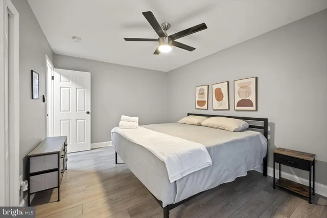 a bedroom with a bed and dresser with wooden floor