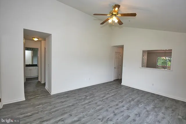 a view of an empty room with a window and wooden floor
