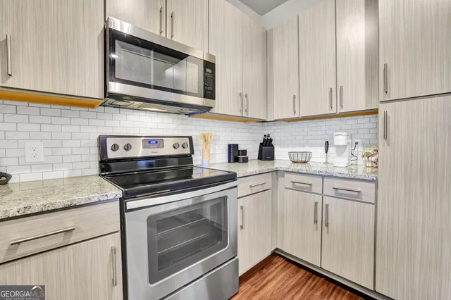 a kitchen with stainless steel appliances granite countertop white cabinets sink and a granite counter top