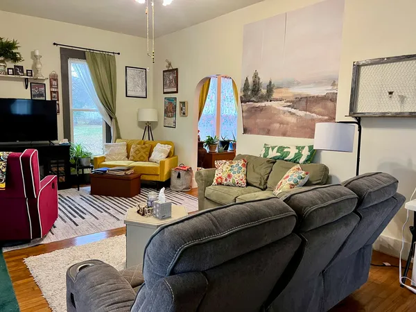a living room with furniture a flat screen tv and a large window
