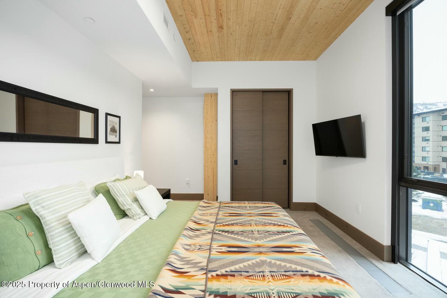 180 Wood Road, Unit 302 Snowmass Village, CO 81615 - Photo 19 of 43 a bedroom with a bed and a flat screen tv