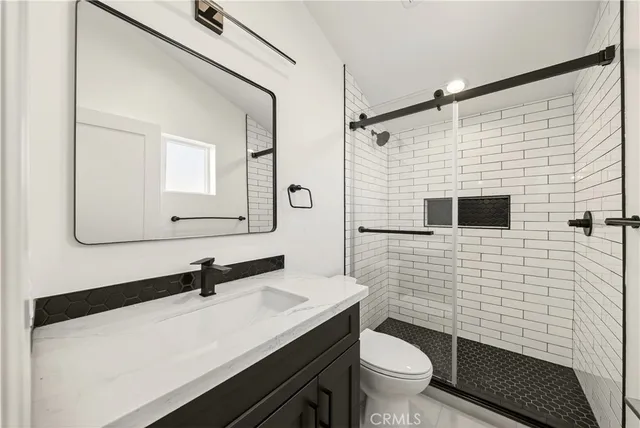 a bathroom with a sink a toilet a mirror and shower