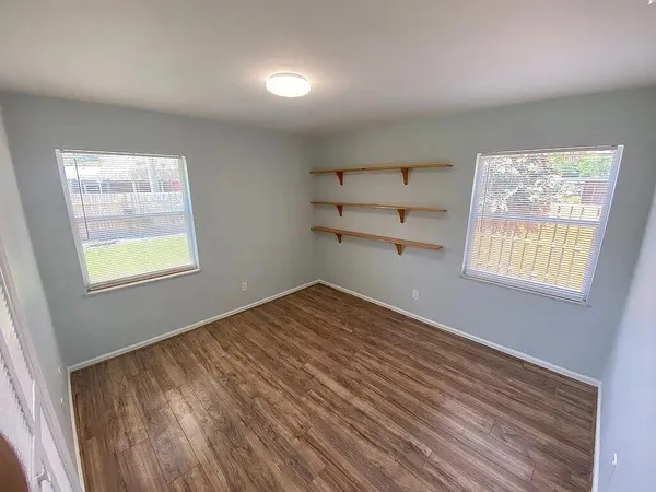 a view of empty room with wooden floor and fan