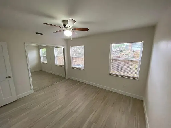 a view of an empty room with a window and wooden floor