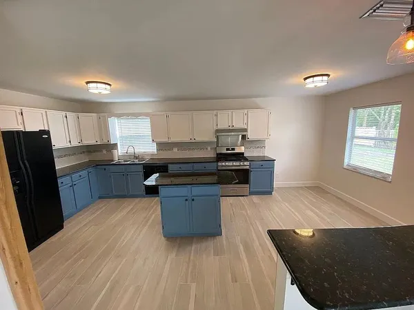 a kitchen with stainless steel appliances kitchen island granite countertop a stove a sink dishwasher and a refrigerator
