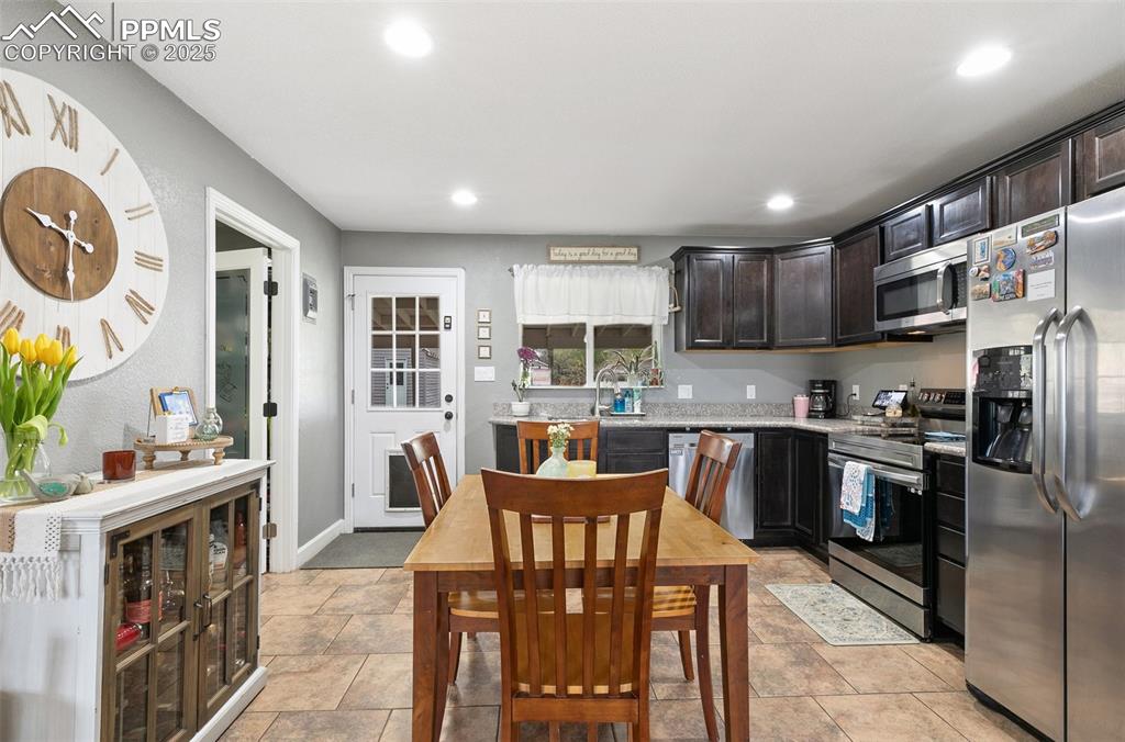 89 Security Boulevard Colorado Springs, CO 80911 - Photo 8 of 29 a kitchen with stainless steel appliances granite countertop a stove top oven a sink a dining table and chairs