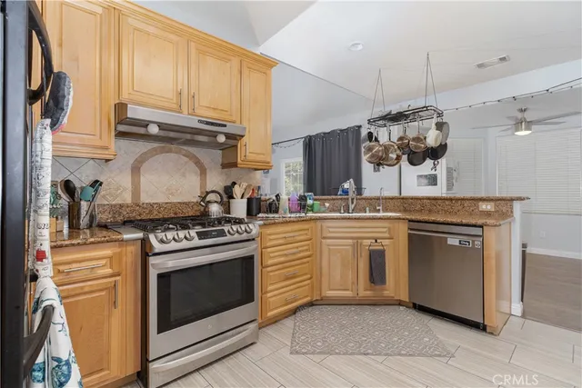 a kitchen with stainless steel appliances granite countertop a stove a sink and a refrigerator