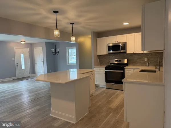 a large kitchen with stainless steel appliances a large counter top a stove a sink and a refrigerator